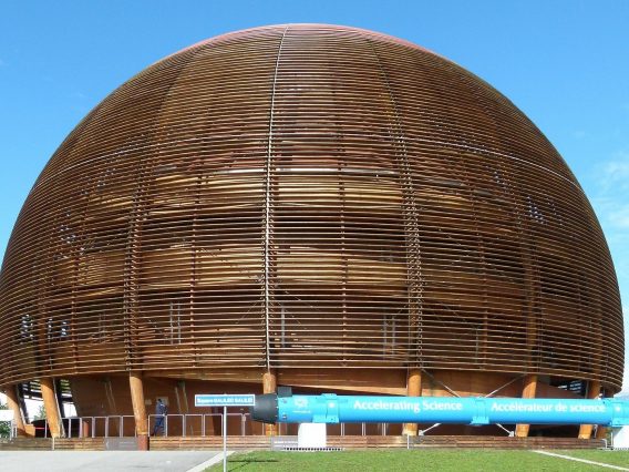 The CERN Building in Switzerland. A wooden dome with a blue pipe in the forefront that writes 